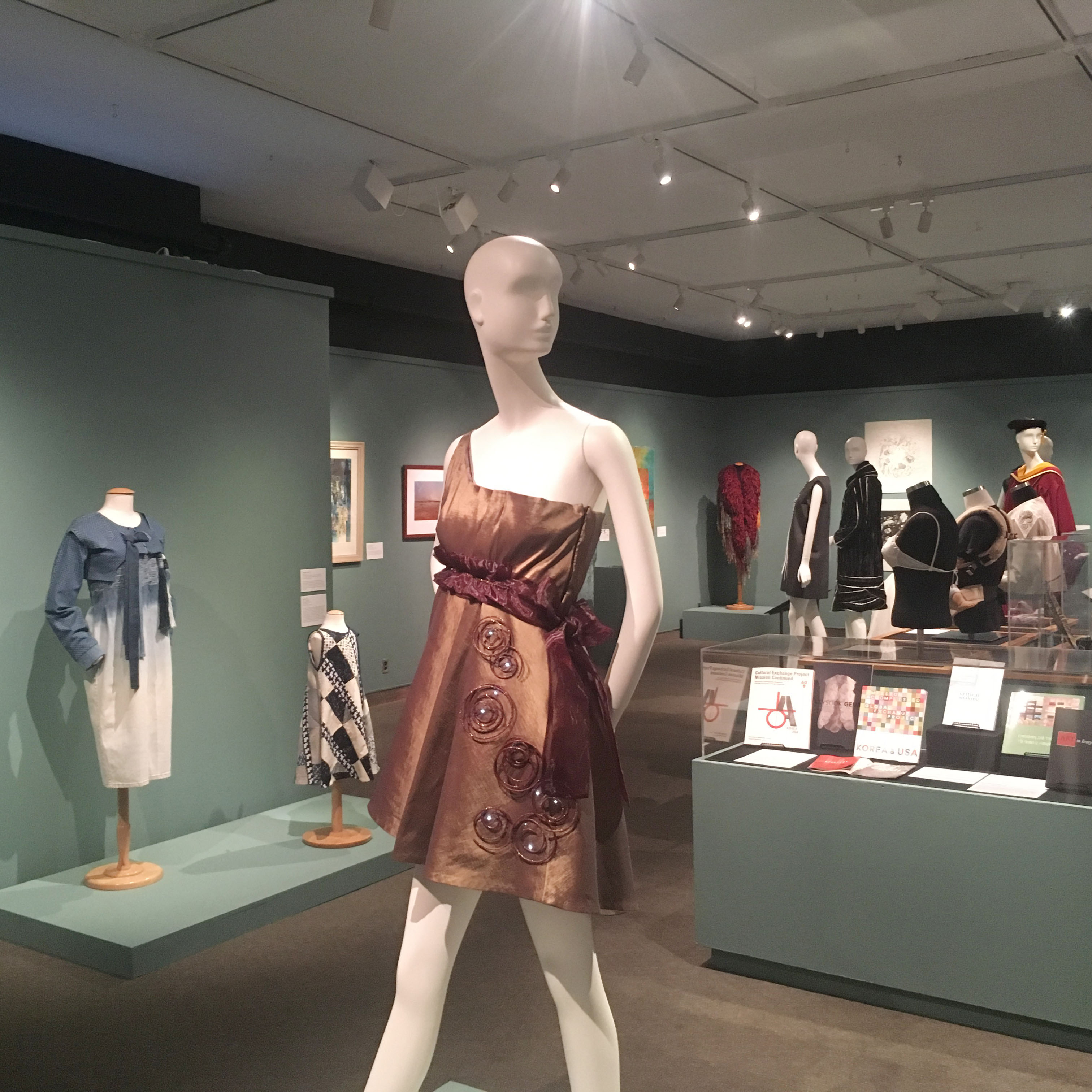 DHA 100 years of graduate education exhibition gallery with clothing and books on display