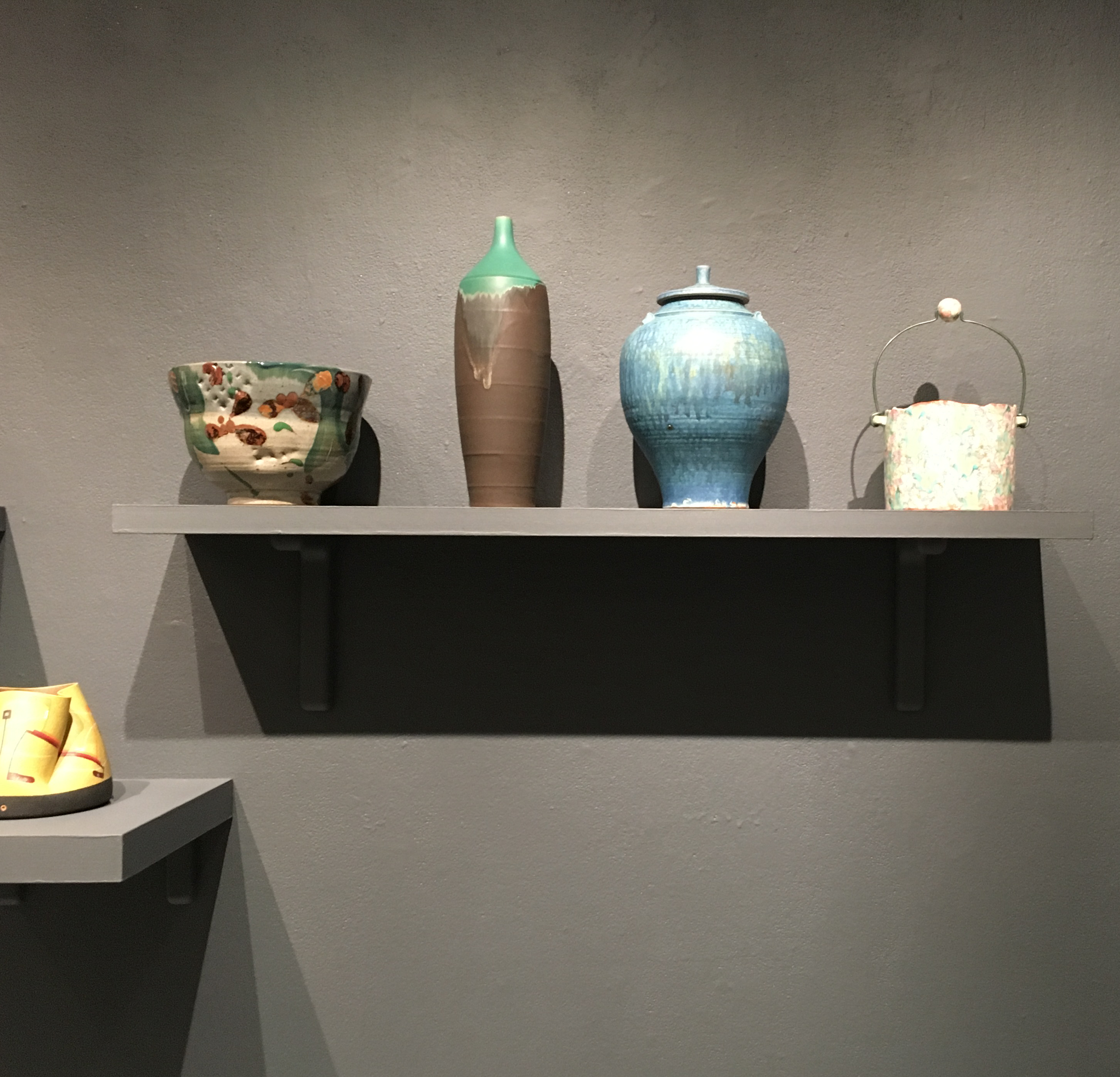 Ruth Crane: A collector's Journey exhibition with various ceramics displayed on a shelfa