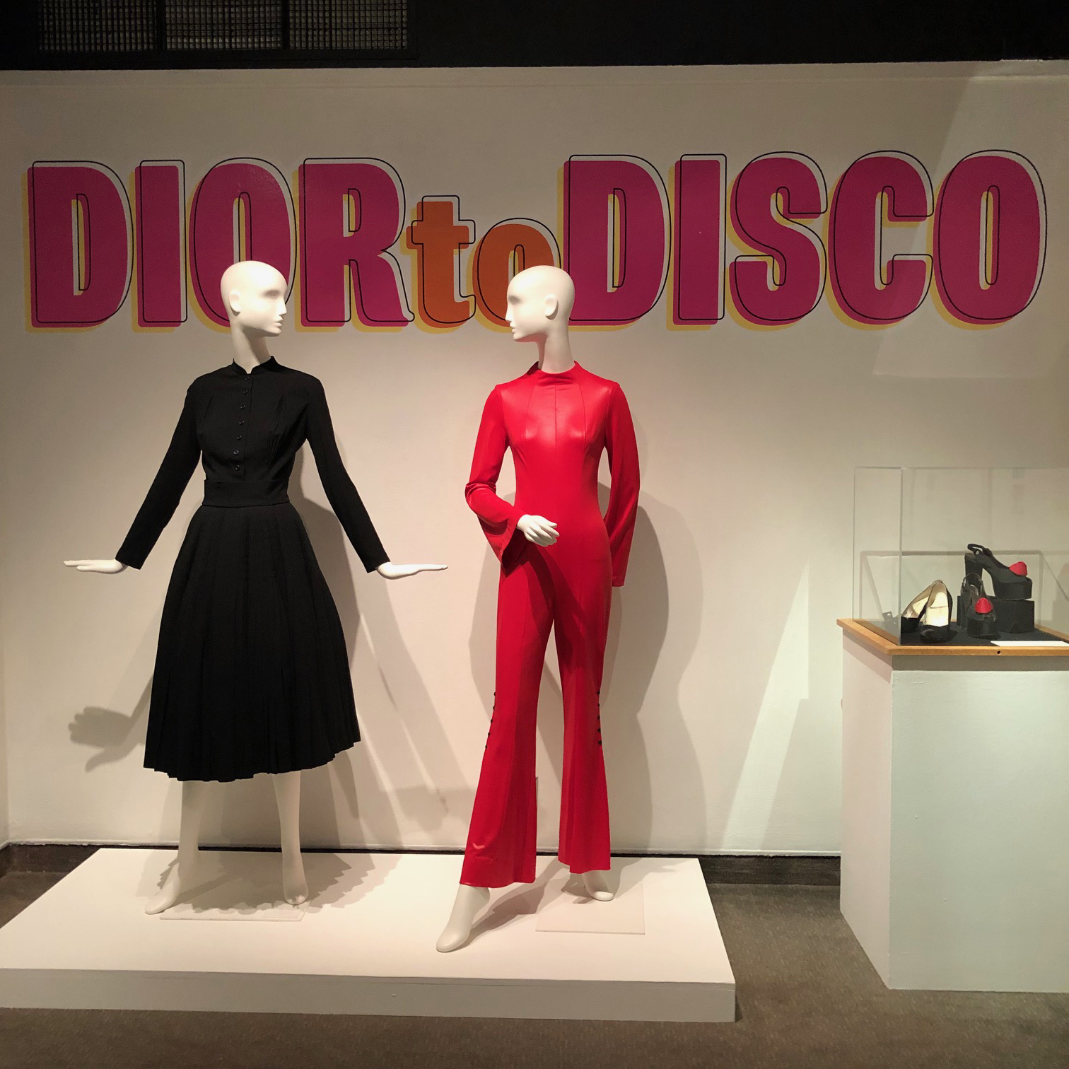 Dior to Disco black dress and red jumpsuit on mannequins