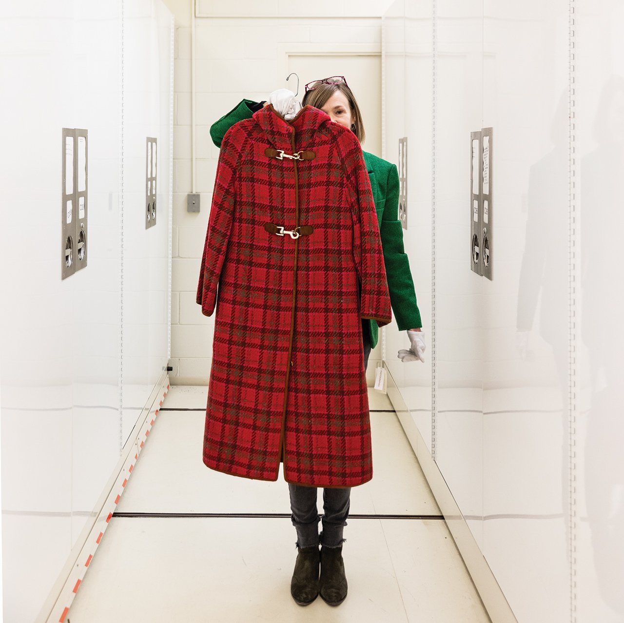Jean McElvain holding up a plaid coat from the Goldstein Collection