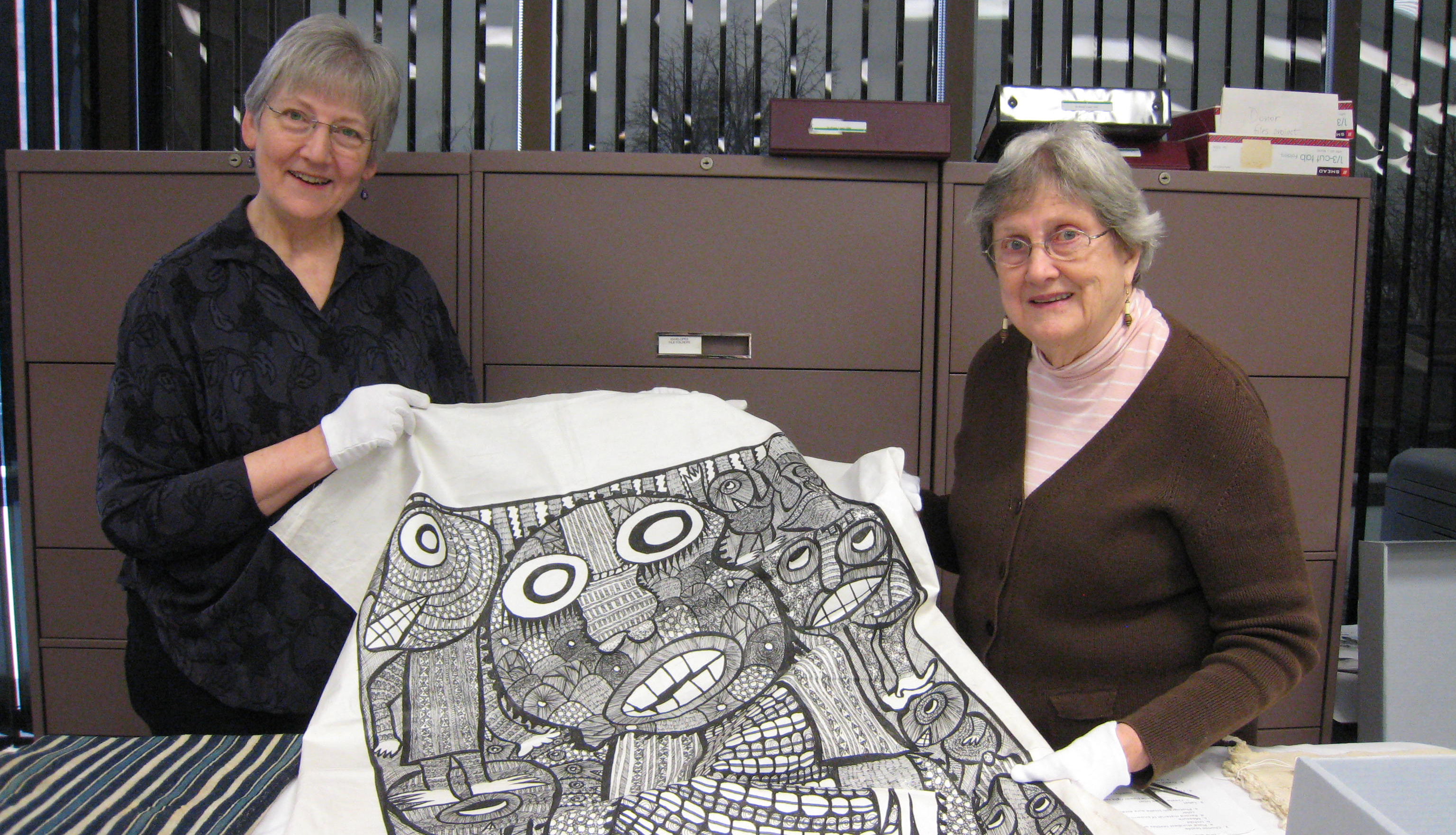 Two people holding a textile that was donated to the Goldstein