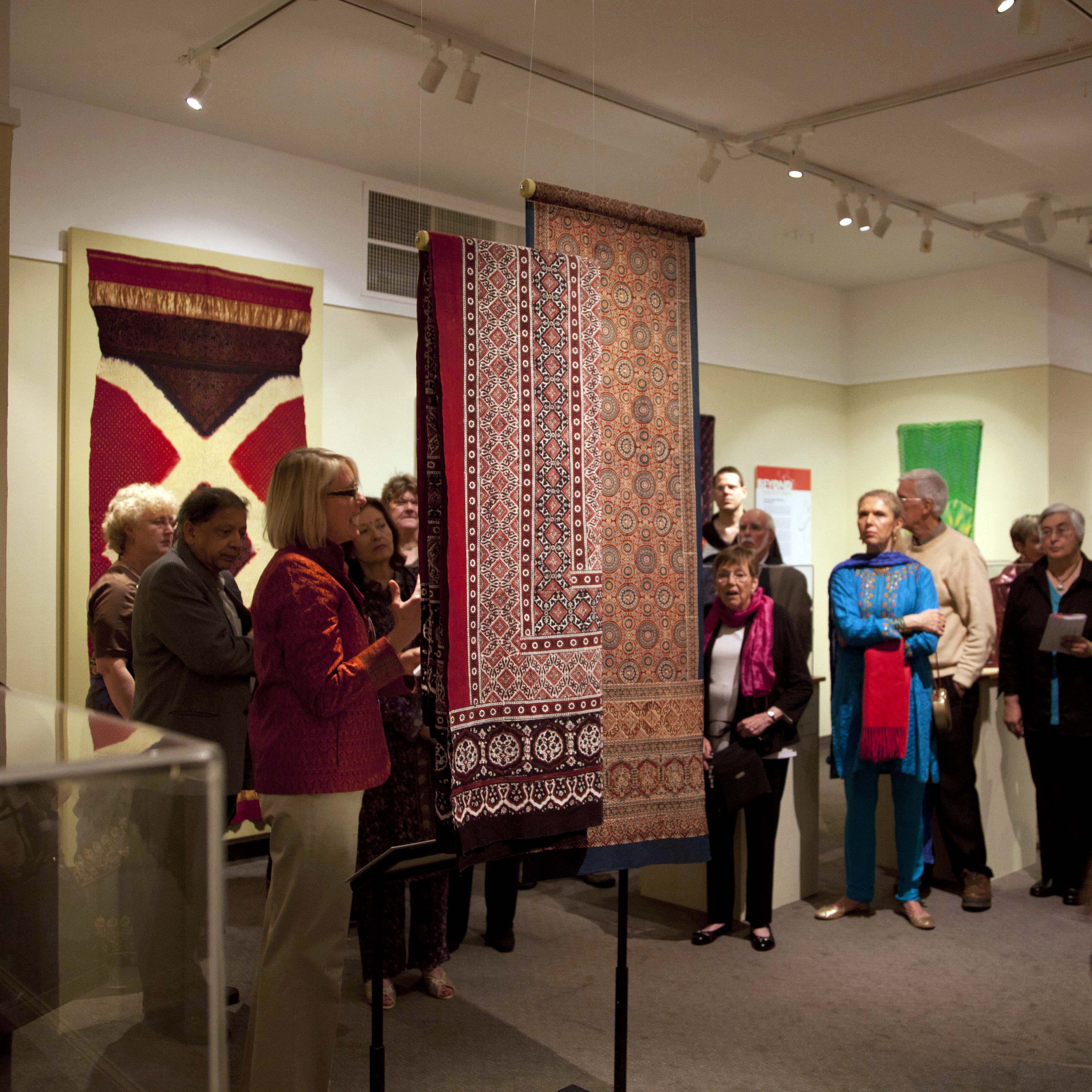 Beyond Peacocks and Paisleys: Handcrafted textiles of India and its neighbors with textiles on view and people milling about