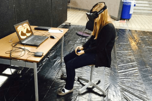 Student sits in chair while using VR equipment.