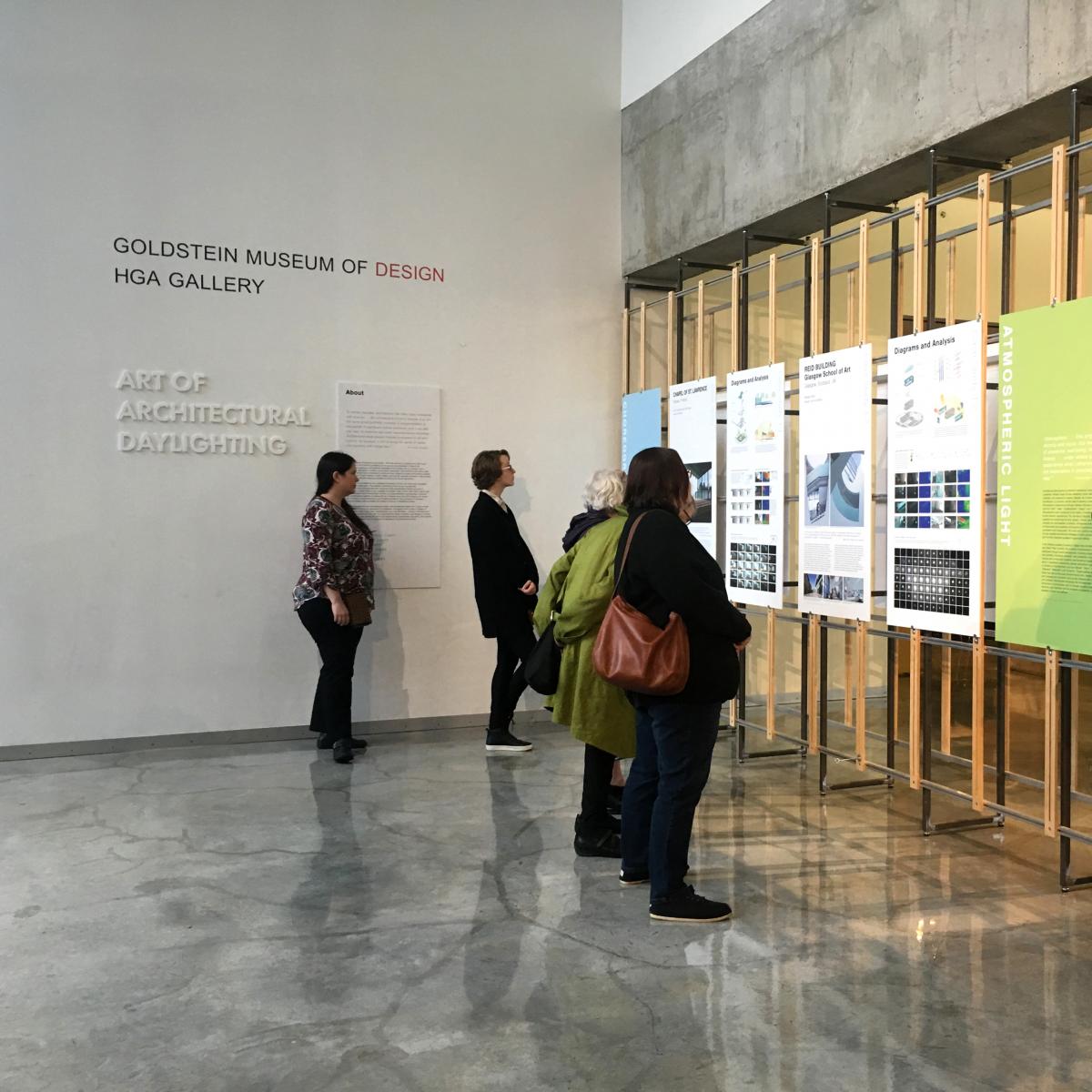 Art of Architectural Daylighting exhibition boards in HGA gallery with four people viewing them