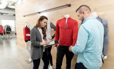Retail student taking notes on merchandise with professional